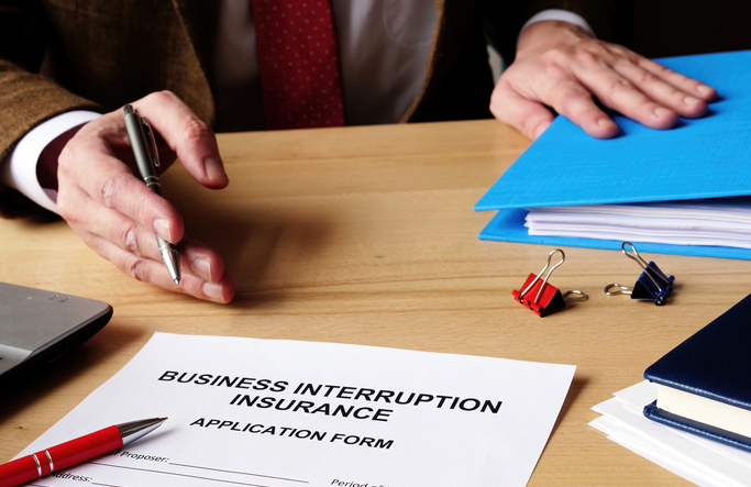 Agent offers business interruption insurance application papers.