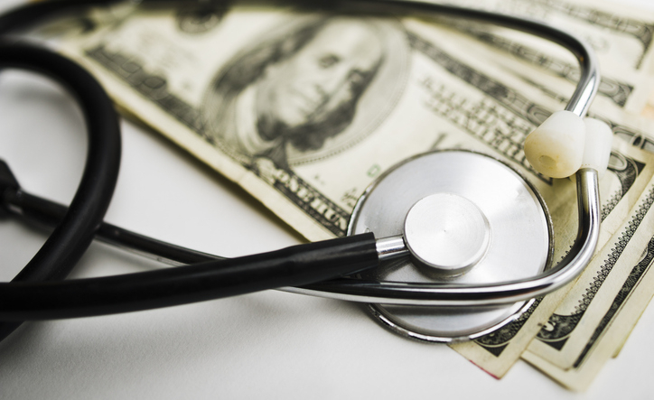 Close up photo of a stethoscope on top of a stack of 100 Dollar bills.