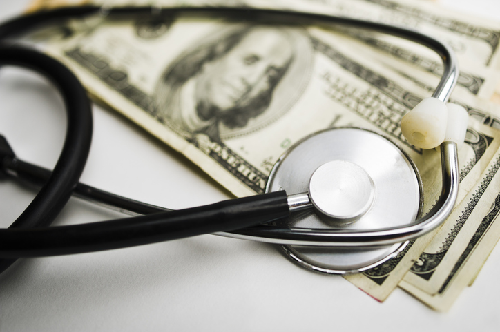 Close up photo of a stethoscope on top of a stack of 100 Dollar bills.