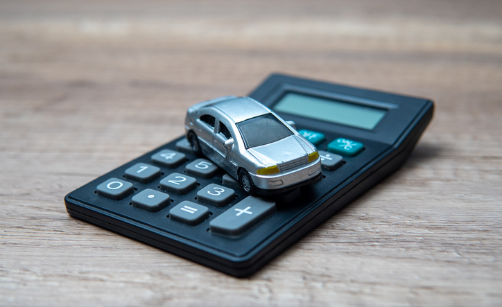 A toy car on top of a calculator, symbolizing the financial aspects of owning a car.