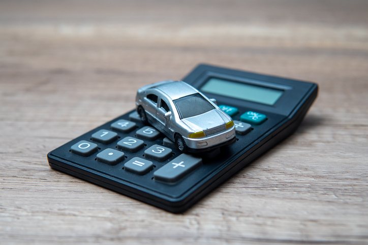 A toy car on top of a calculator, symbolizing the financial aspects of owning a car.